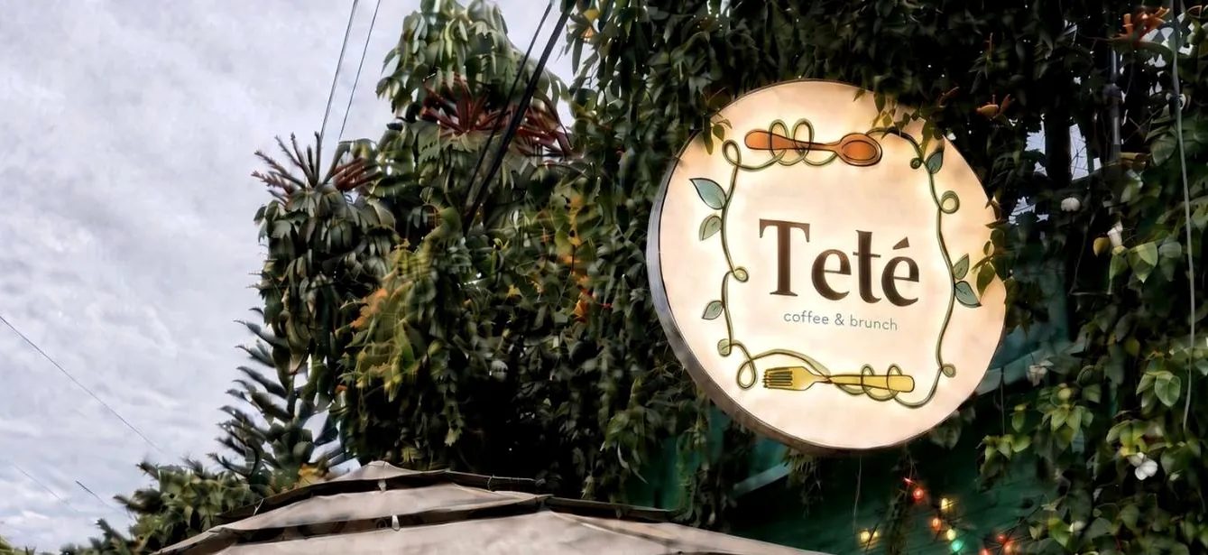 El letrero de Teté iluminado entre la enredadera, contra el cielo de Cuernavaca